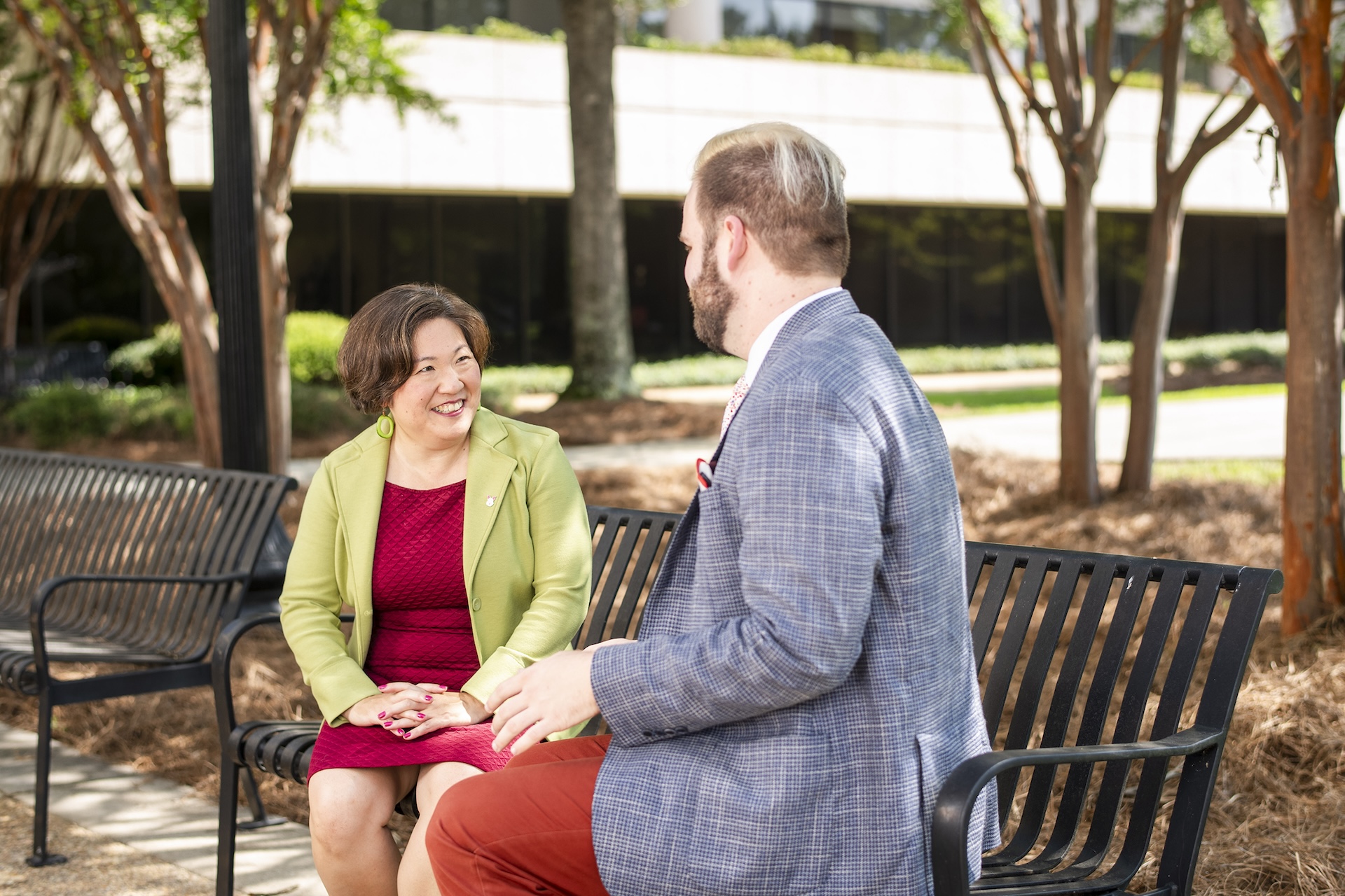 A professor and a student chat on a bench in the back courtyard at the Law School. 