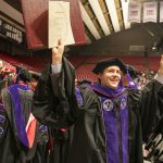 Alabama Law student celebrates with diploma in the air after graduation.