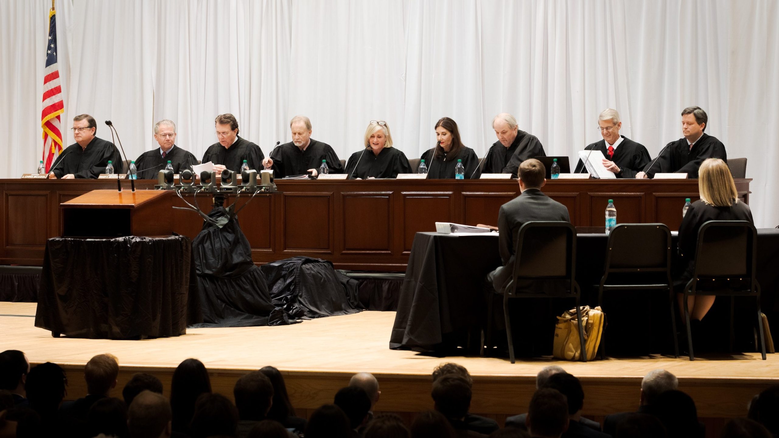 The Justices of the Supreme Court of Alabama sit on the stage in the main auditorium at the Moody Music Building. 