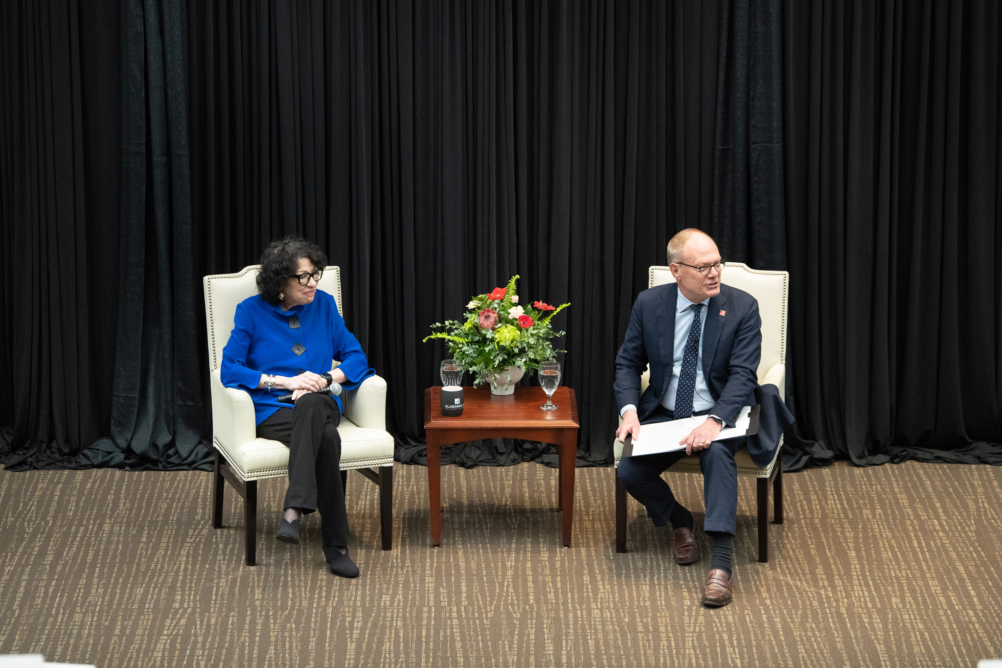 Justice Sonia Sotomayor sits in a chair with Dean Bill Brewbaker, also in a chair. They are not looking at the camera and Dean Brewbaker appears mid-sentence.