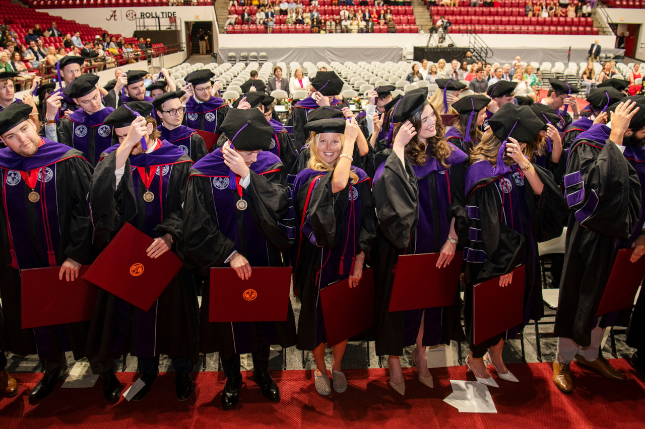 A group of law school graduates move their tassels during the University of Alabama School of Law commencement ceremony.