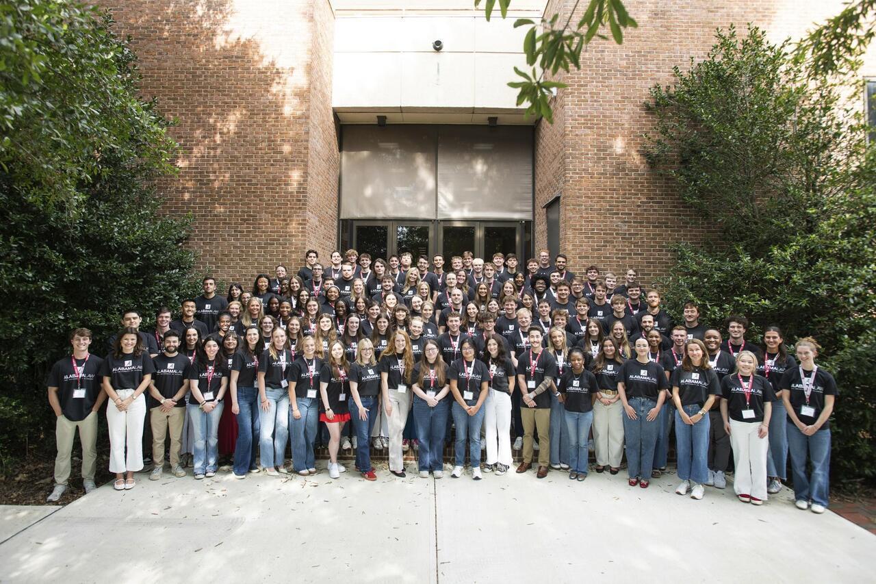 Alabama Law's incoming Class of 2029 students posing together in Alabama Law T-shirts outside the law school building